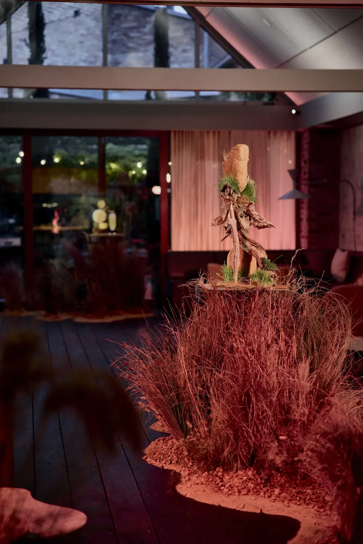 Sculptural grass and driftwood installation in The Atrium at Half Acre at dusk