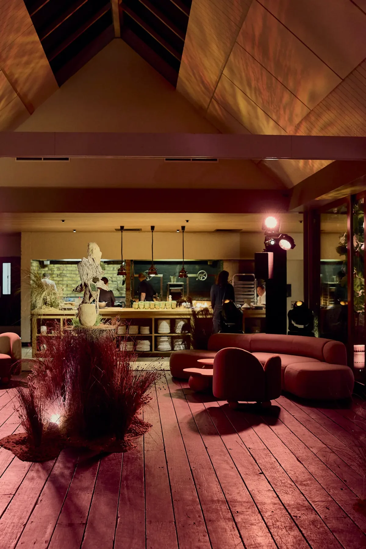 Lounge seating and the open kitchen in The Atrium at Half Acre, lit in warm evening tones