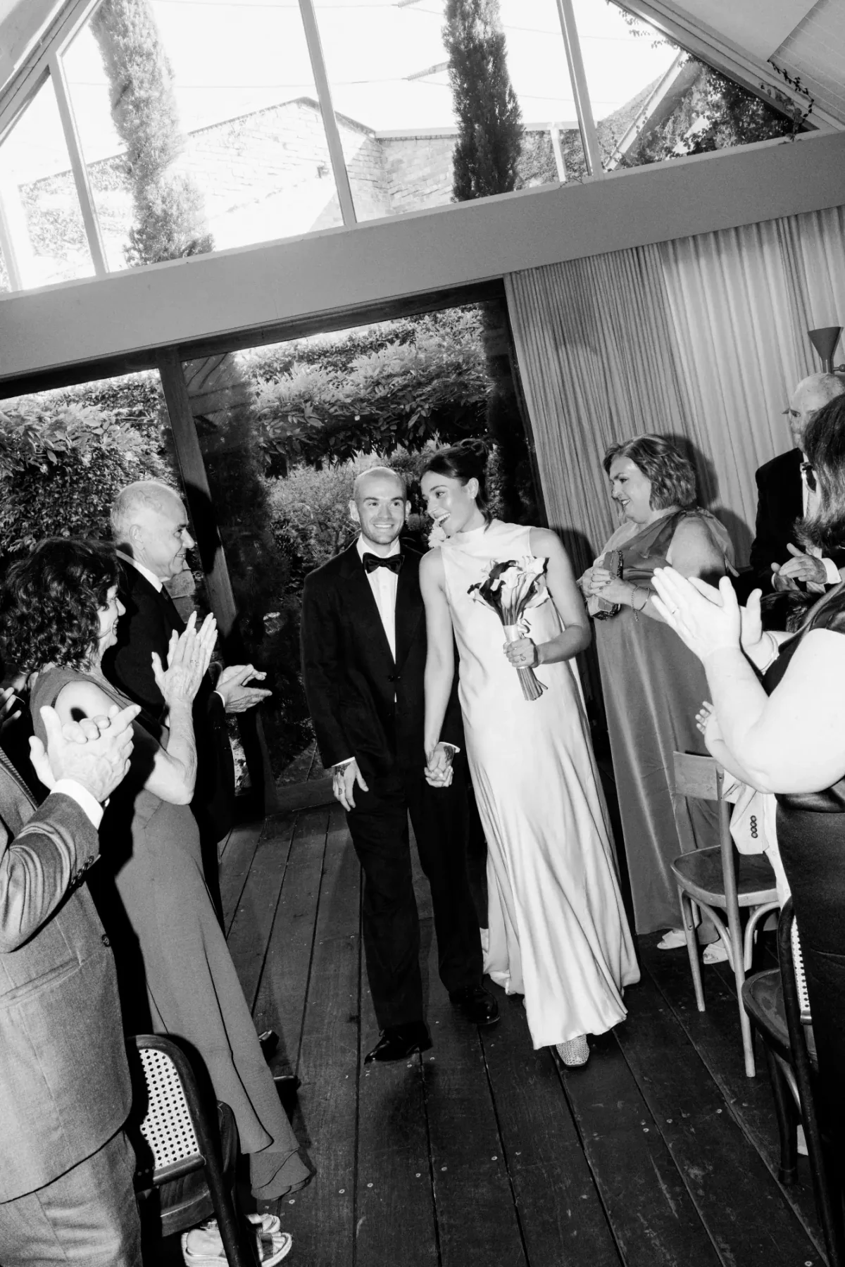 Newlyweds walking down the aisle in The Atrium at Half Acre as guests applaud