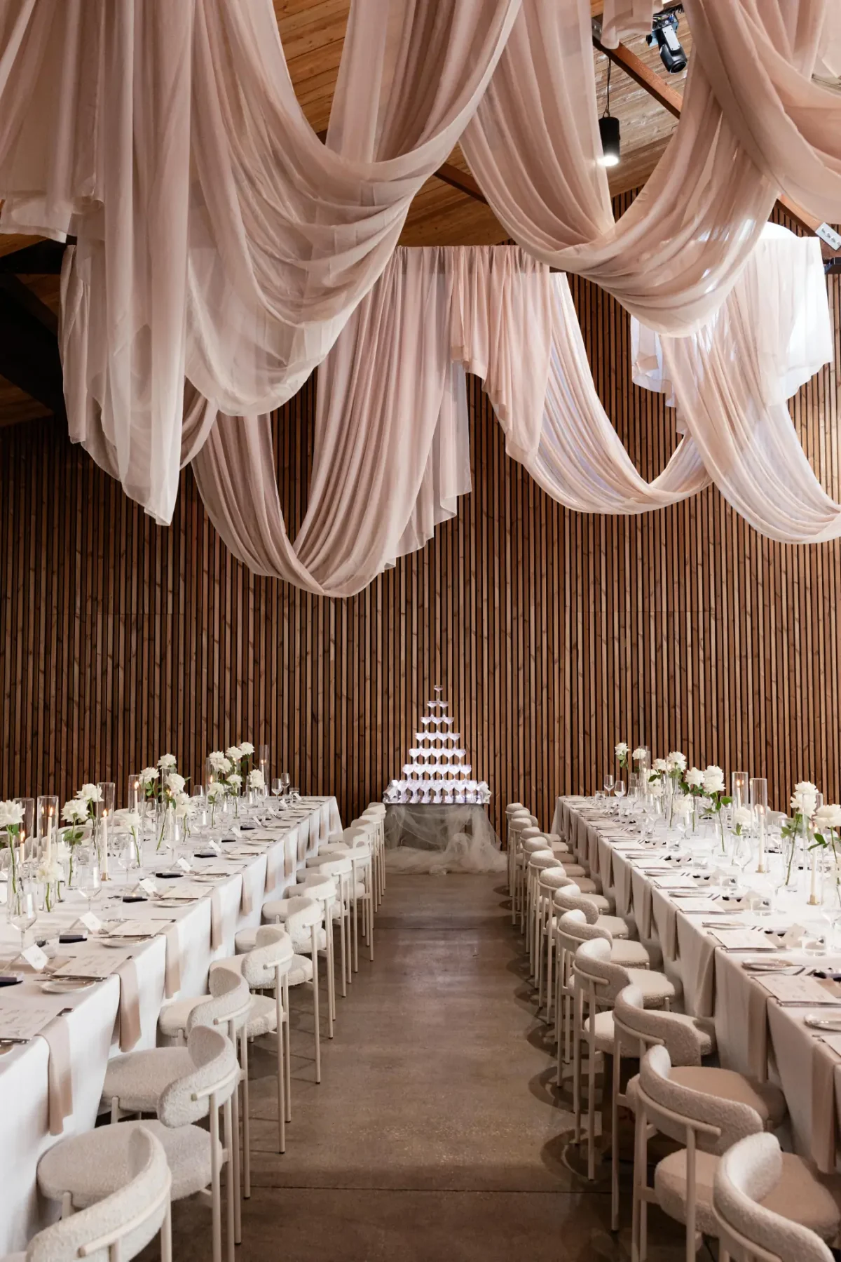 Long reception tables beneath draped blush fabric and a champagne tower in The Mill at Half Acre