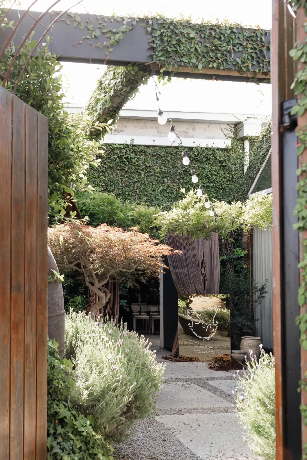 View through the timber gate into the ivy-covered courtyard at Half Acre set for a wedding