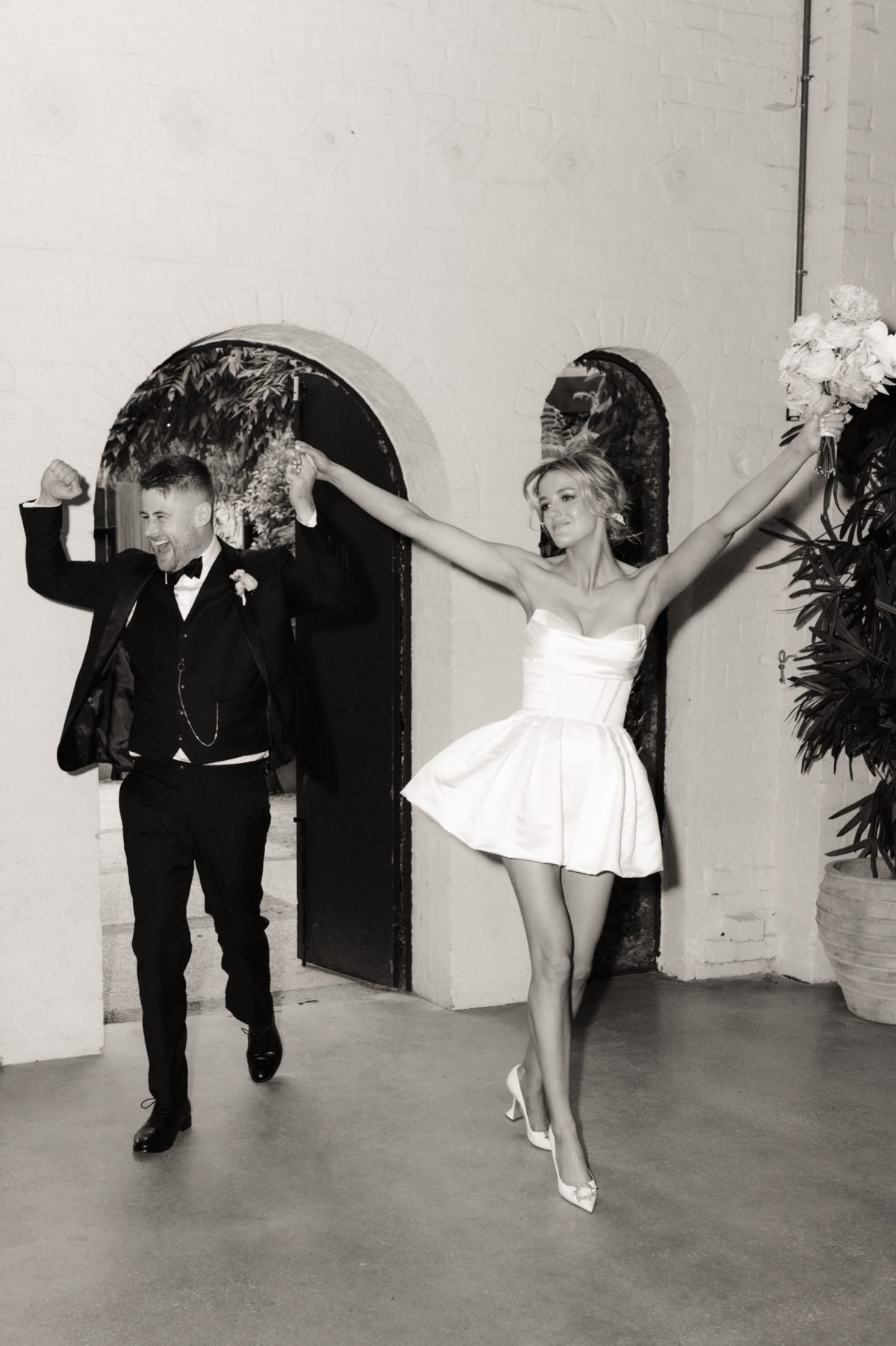 Black and white photo of a bride and groom dancing in front of the arched doors at Half Acre